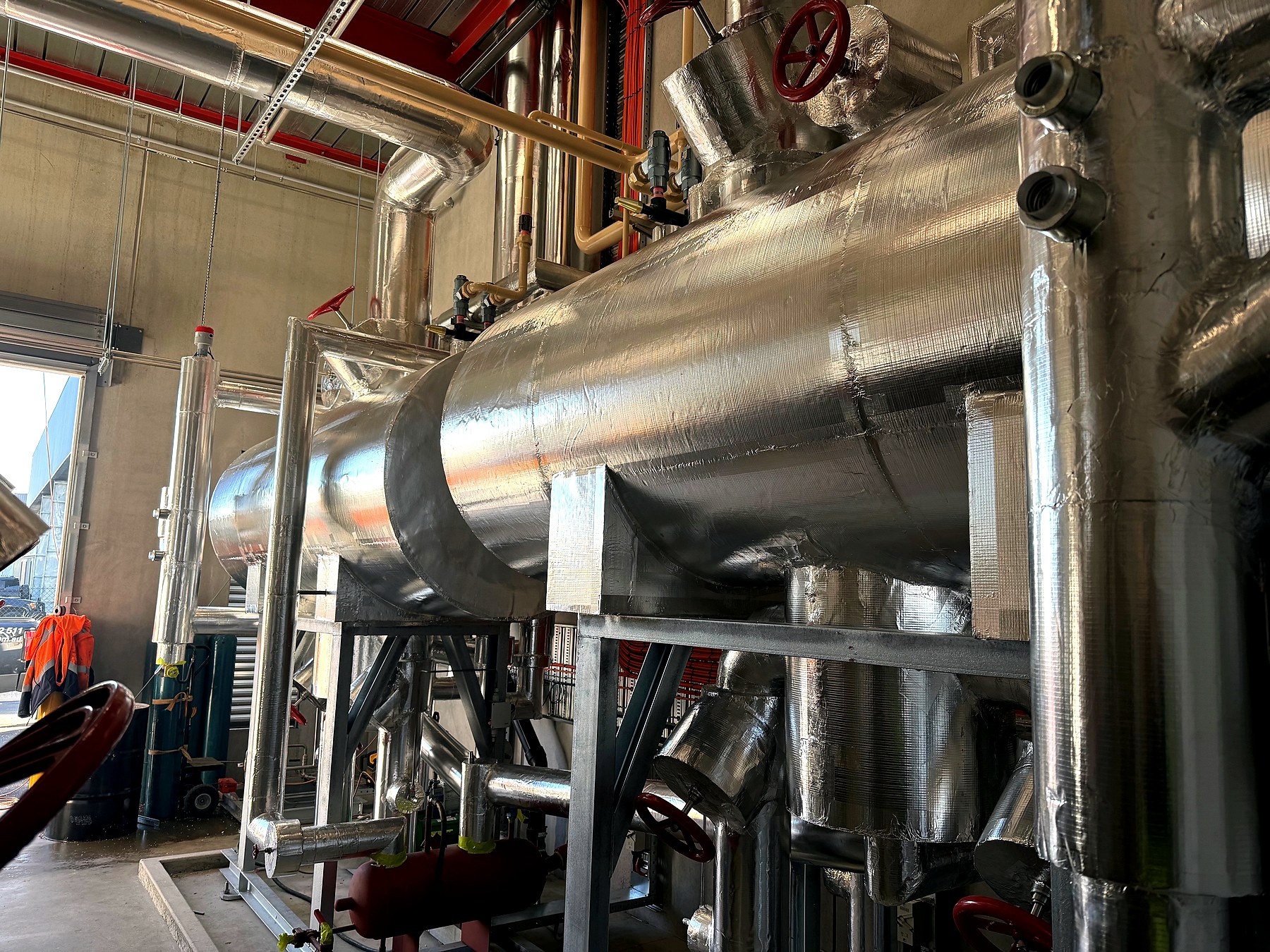 Large horizontal industrial pressure vessel wrapped in foil-faced thermal insulation